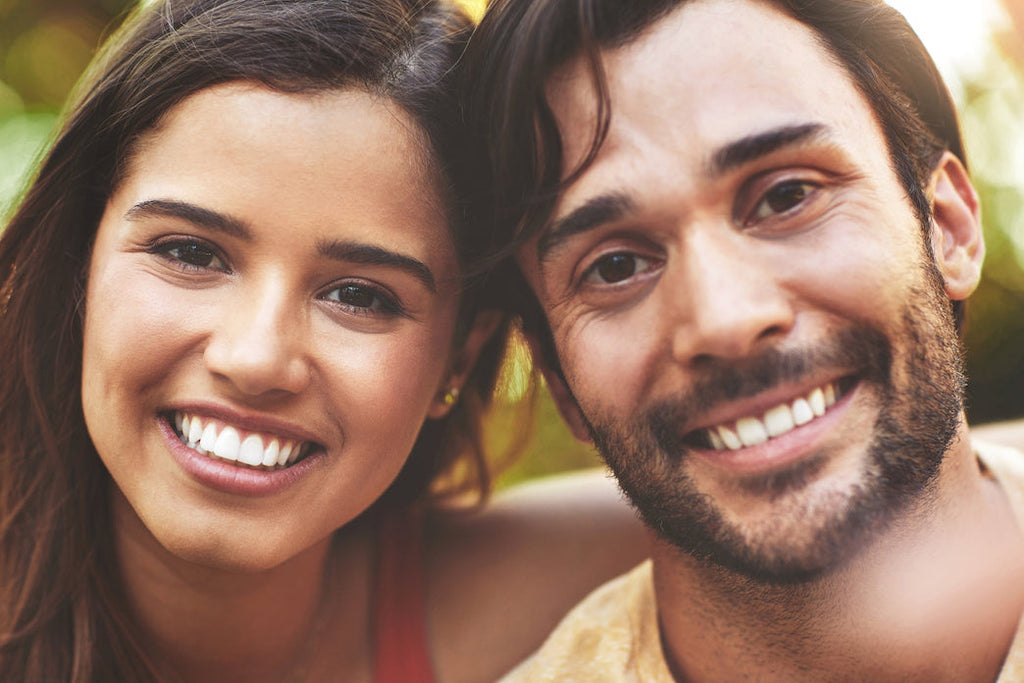 A photo of an affectionate young couple smiling at the camera.