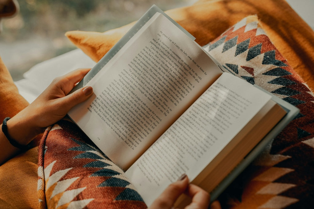 A close-up photo of an open book being read on a person's lap.