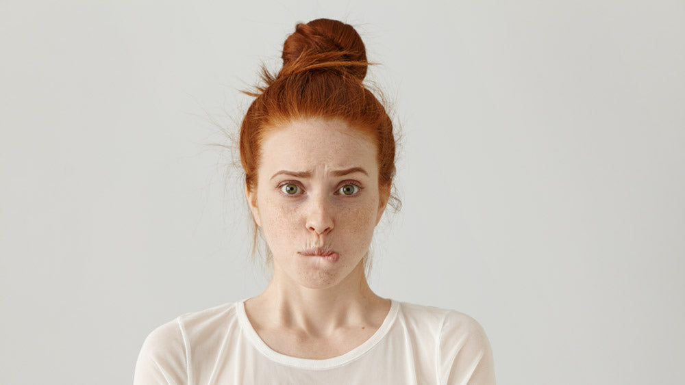 A portrait of woman with red hair biting her lip thinking "how to make anxiety go away forever."