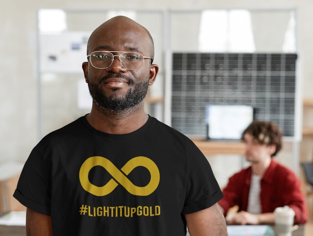 Neurodivergent vs neurodiverse: a man is wearing a black t-shirt with a gold infinity symbol on it.