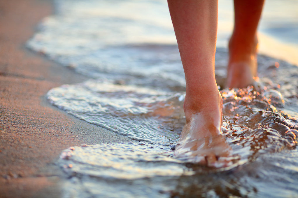 Poems about anxiety: a calming photo of a person's feet walking on a beach at dusk.