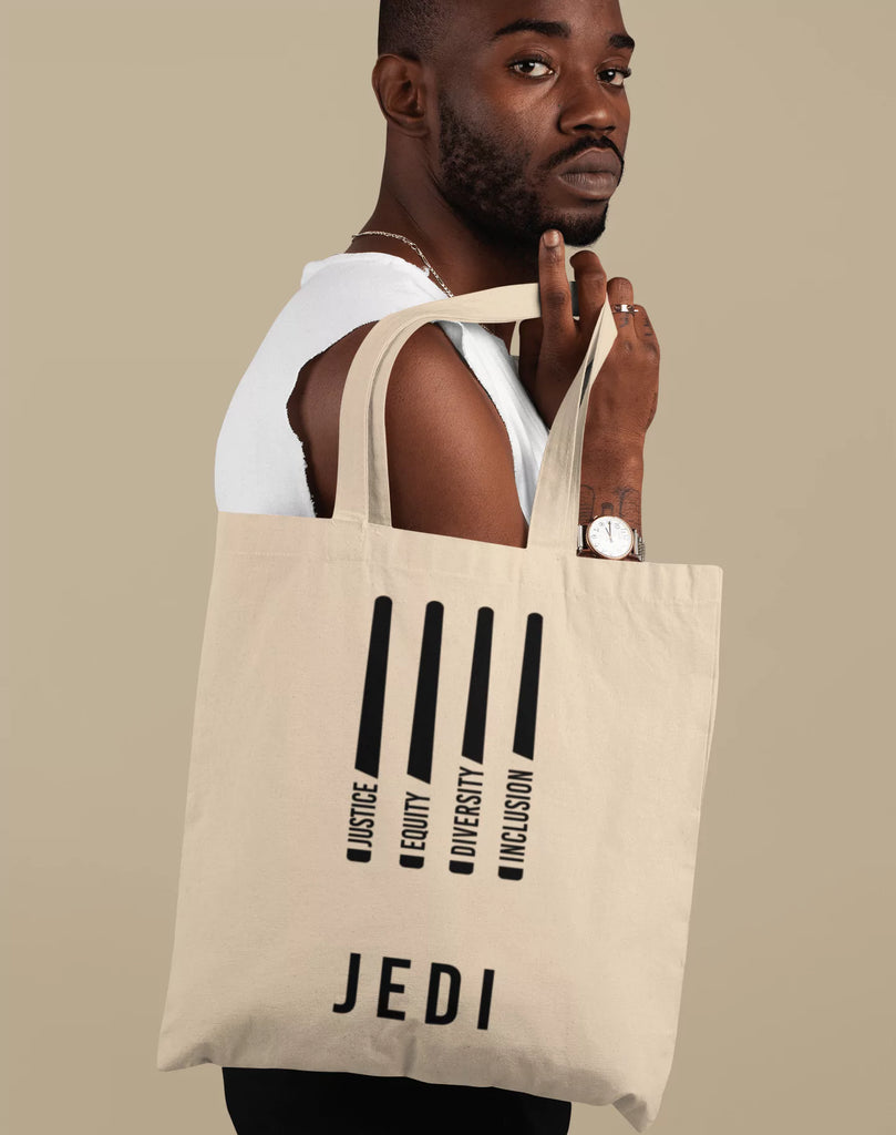 JEDI Justice Equity Diversity Inclusion organic tote bag with white DEI design, held by a person showcasing social justice and JEDI values.