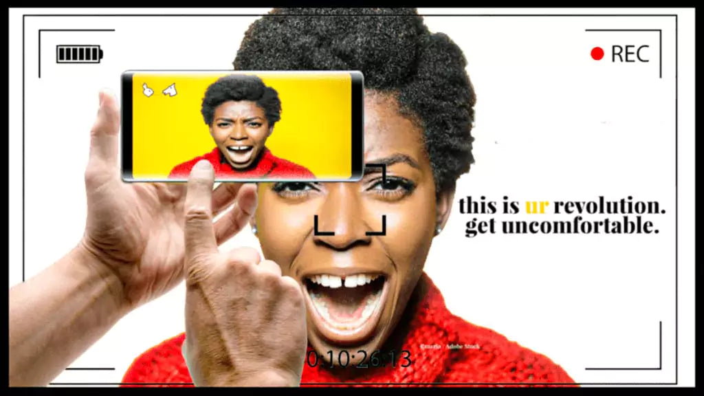 Bold Black woman wearing a red sweater, shouting with passion, framed within a digital camera recording screen. A hand holds a smartphone capturing her face, emphasizing digital storytelling. The text reads: "This is UR revolution. Get uncomfortable."