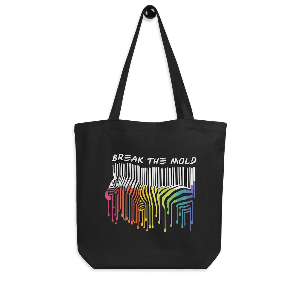 A photo of a black organic break the mold tote bag. In the middle of the break the mold tote is a graphic of zebra in the silhouette of a barcode. The top half of the zebra are vertical black stripes, which then change just below the back into the colors of the rainbow. The bottom of each stripe has a paint drip mark. Just above the zebra's back is the phrase, in upper case, 'break the mold.'